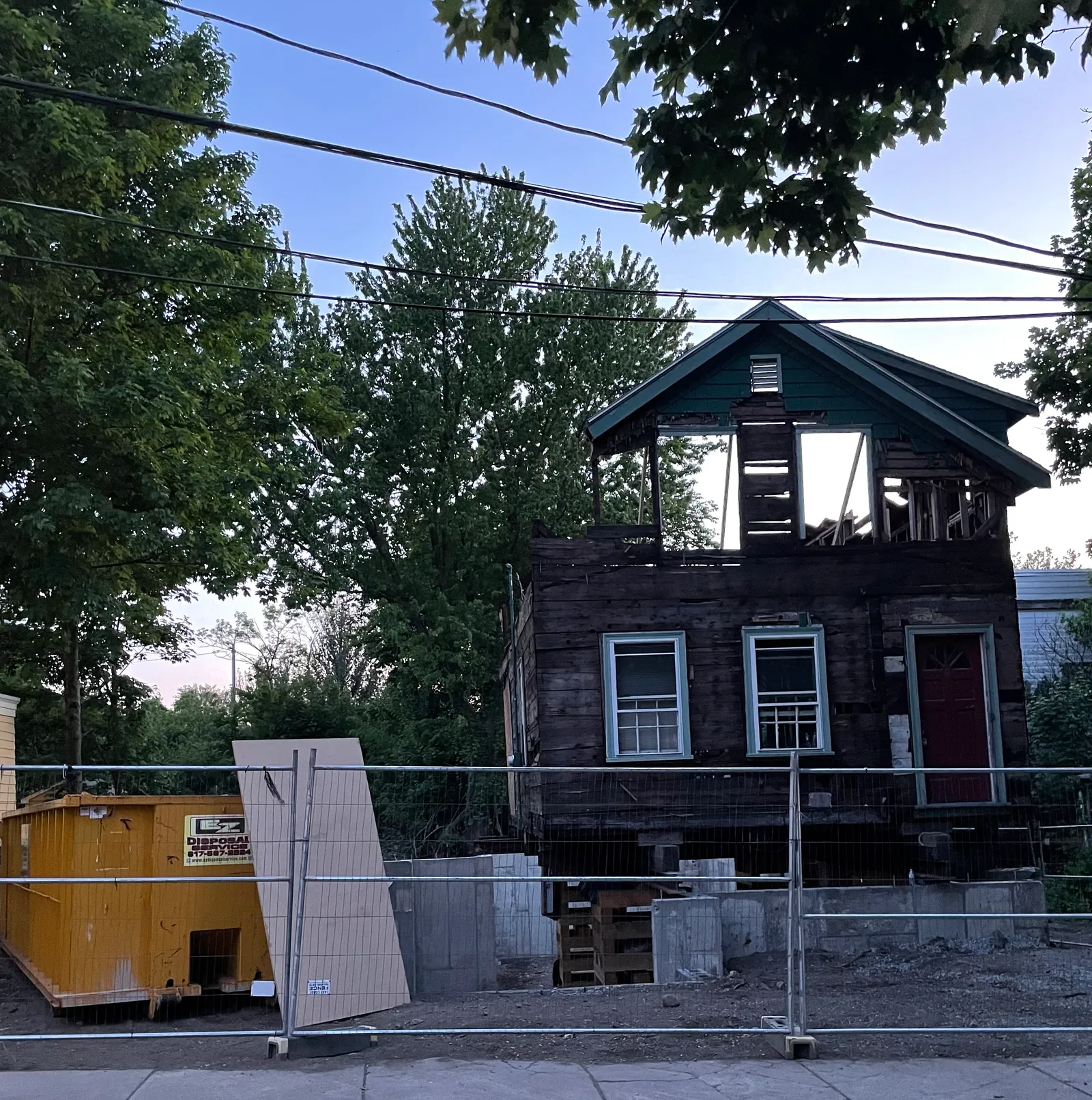 Partially demolished home with dumpster in front