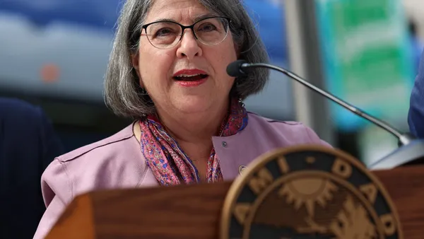 A woman speaks at a lectern with the Miami-Dade County, Florida, insignia on its front.