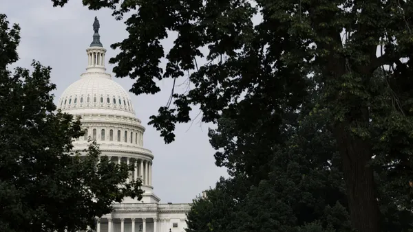 The U.S. Capitol dome appears in the background behind two trees.