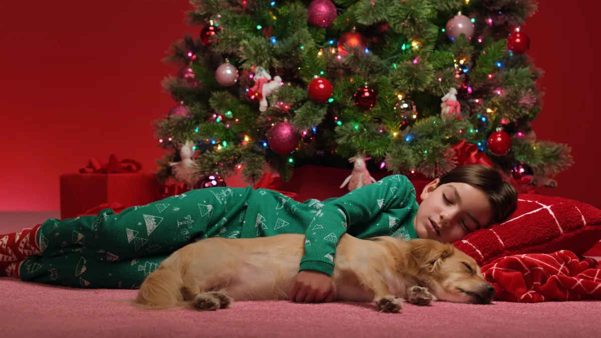 A child sleeps with a dog in a holiday setting for Target's 2023 holiday campaign