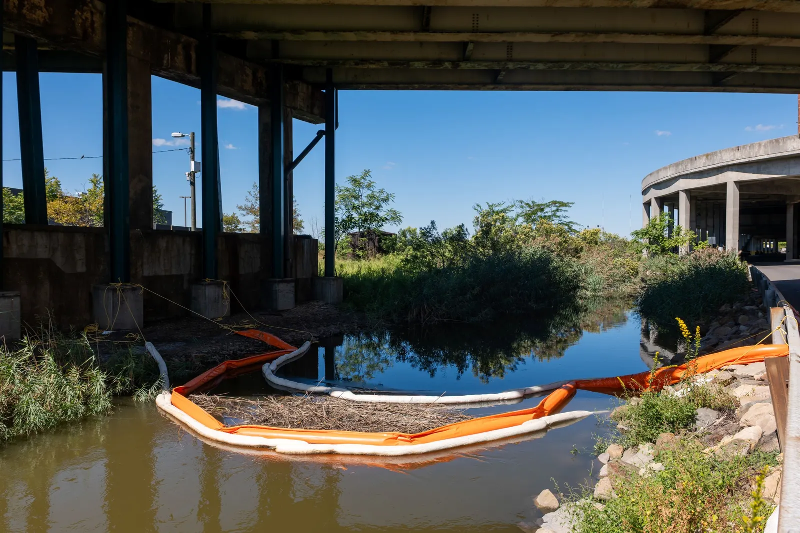Hoses and pumps and barriers line a creek.