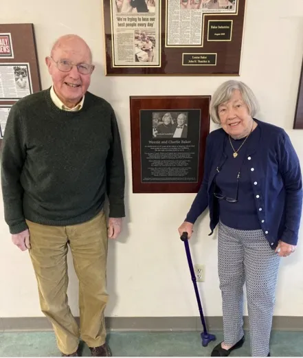 Two people stand in front of an awards plaque at Baker Industries