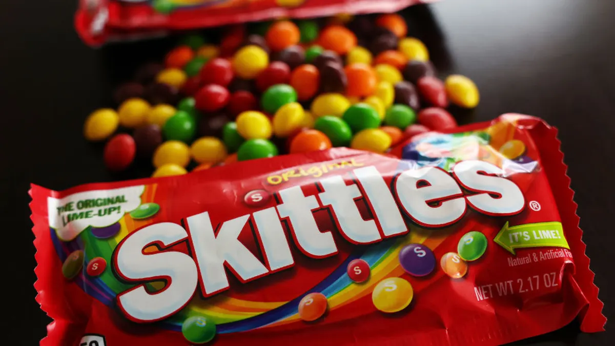 A package of Skittles sits on a table.