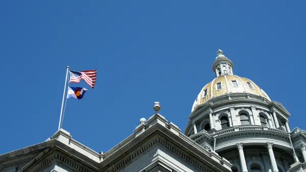 Colorado and United States flags fly above the Colorado State Capitol in Denver