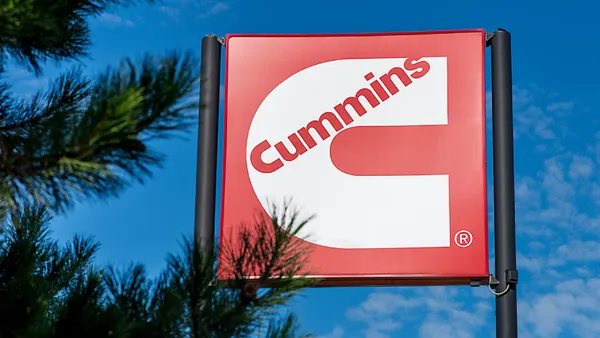 A Cummins sign with pine tree branch needles in the foreground.