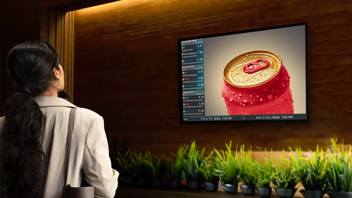 Woman looking at a red soda can on large TV screen.