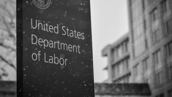 A black and white photograph of the US Department of Labor's sign, with its insignia.