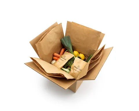 An open shipping box with food, paper-based cool packs and a paper thermal liner.