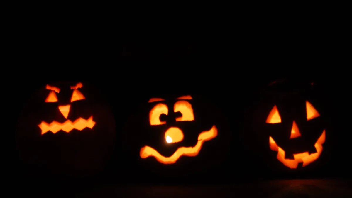 A row of carved jack-o-lanterns glows in the darkness.