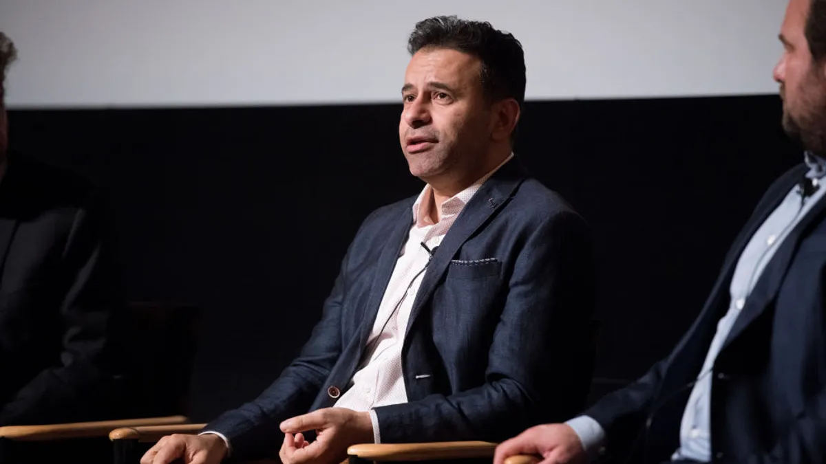 A person in a dark suit speaks on stage during a film screening.