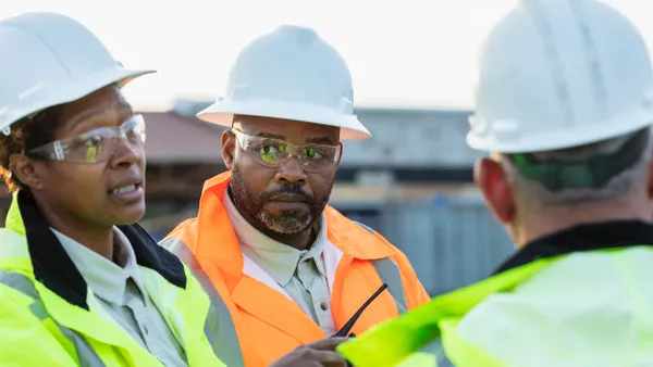 Diverse construction workers talk on a jobsite.