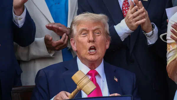 Donald Trump, holding a gavel, celebrates his signing of the One Big Beautiful Bill Act.