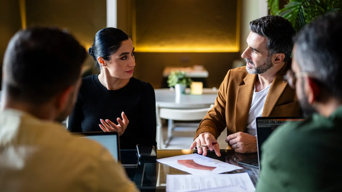 Confident Iranian businesswoman explaining to male colleagues in meeting