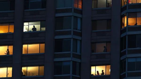 People sillhouetted in a residential building at night.