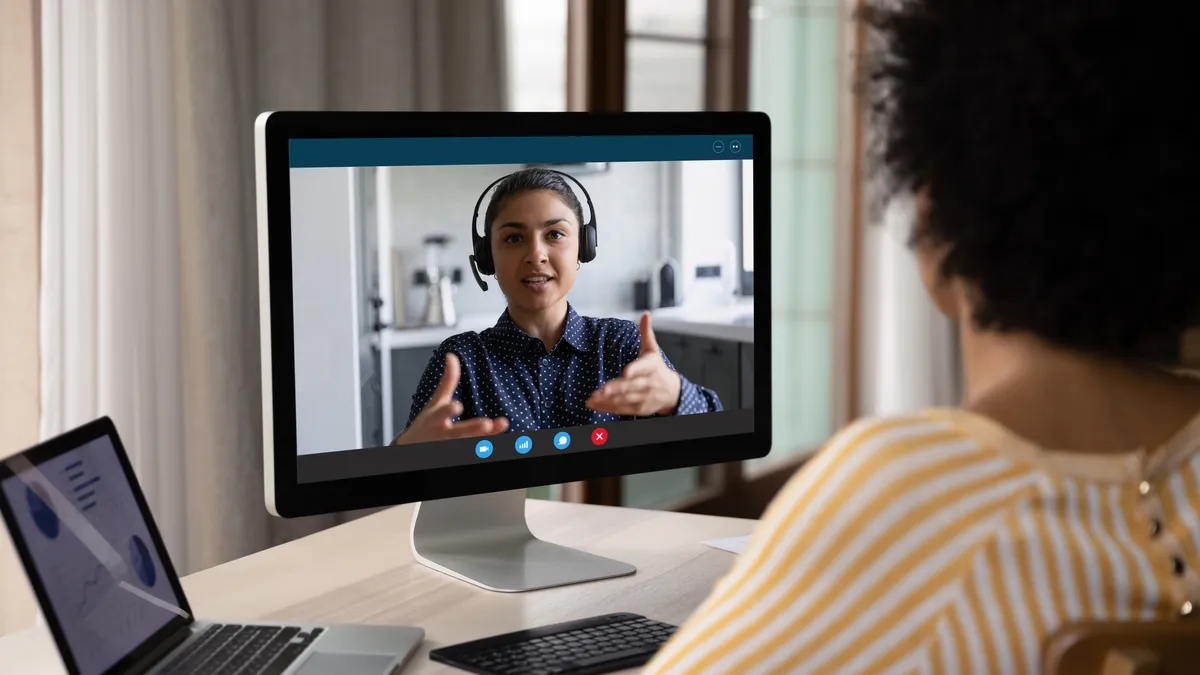 Female business coworkers discussing project marketing report on distance virtual chat at computer monitor.