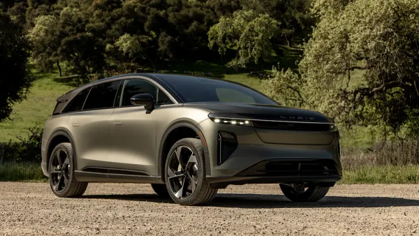 A Lucid Gravity electric SUV parked outdoors with greenery in the background.