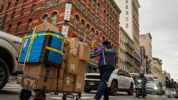 A FedEx delivery person pulls a hand truck with packages.