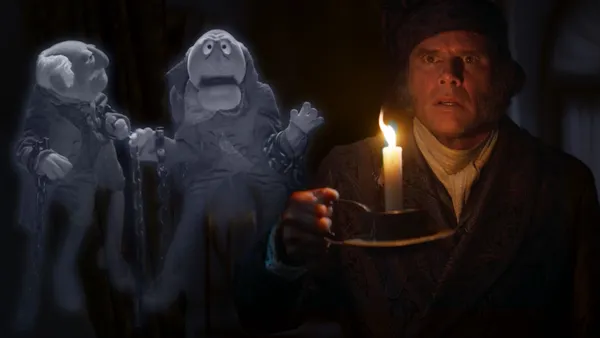 Actor Walton Goggins portrays Ebeneezer Scrooge in a dark scene where he is haunted by the ghosts of Muppets Statler and Waldorf.