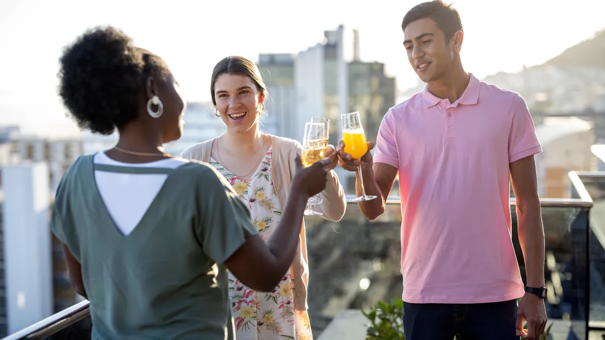 Young adults enjoying cocktails on balcony overlooking city