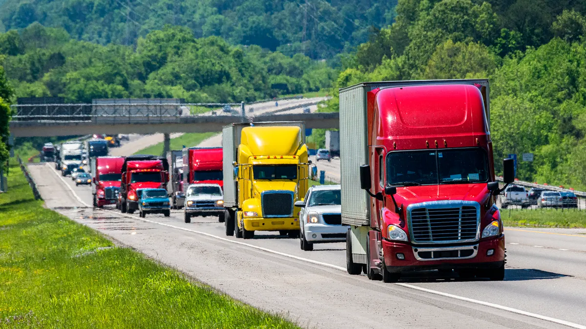 Trucks and vehicles drive along a road close together.