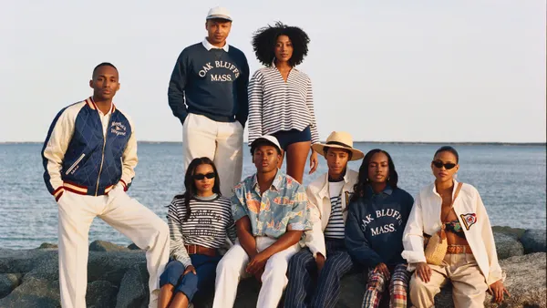 Eight people pose on a shoreline wearing clothing with Oak Bluffs logos.