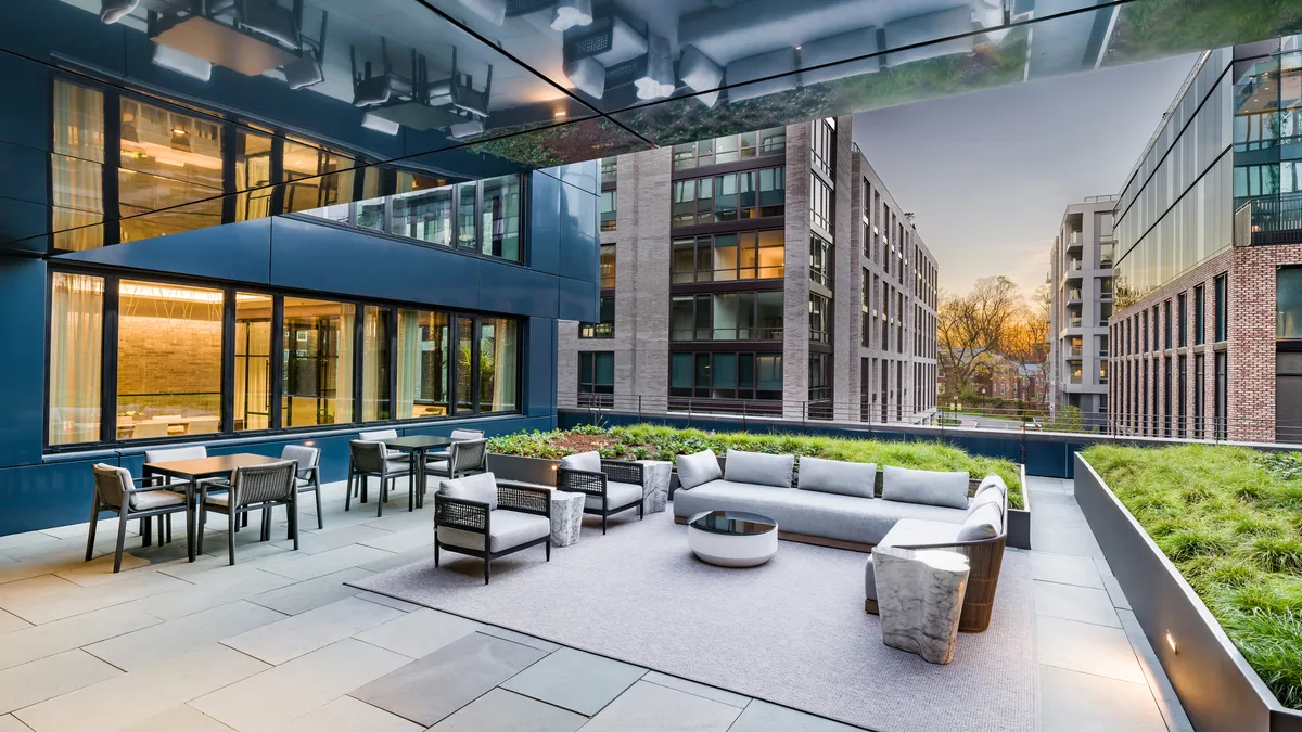 A raised patio in an apartment building with tables, chairs, and sofas.