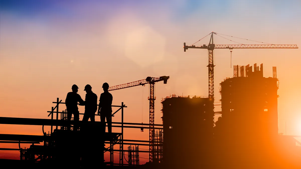 Silhouette of engineer and construction team working at site over blurred background