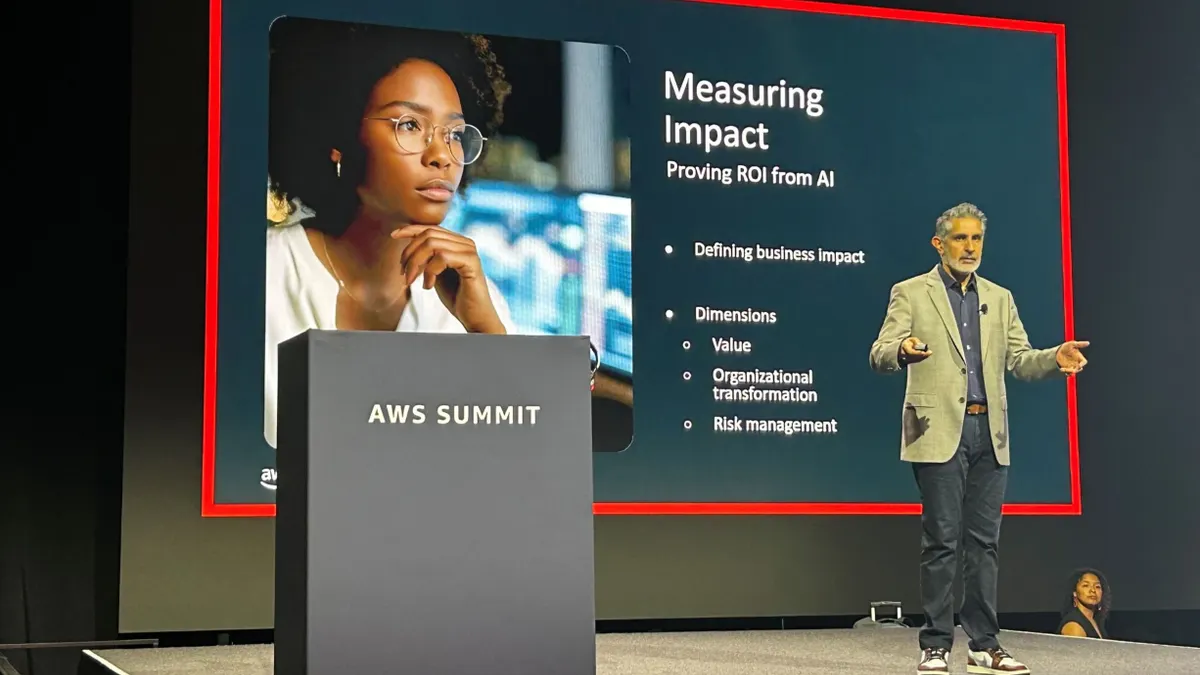 A man stands on stage next to a podium presenting to an audience