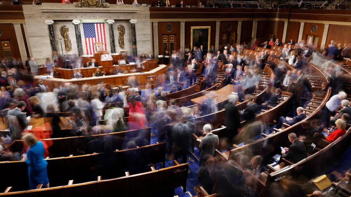 blurred members of congress shuffle around in chamber