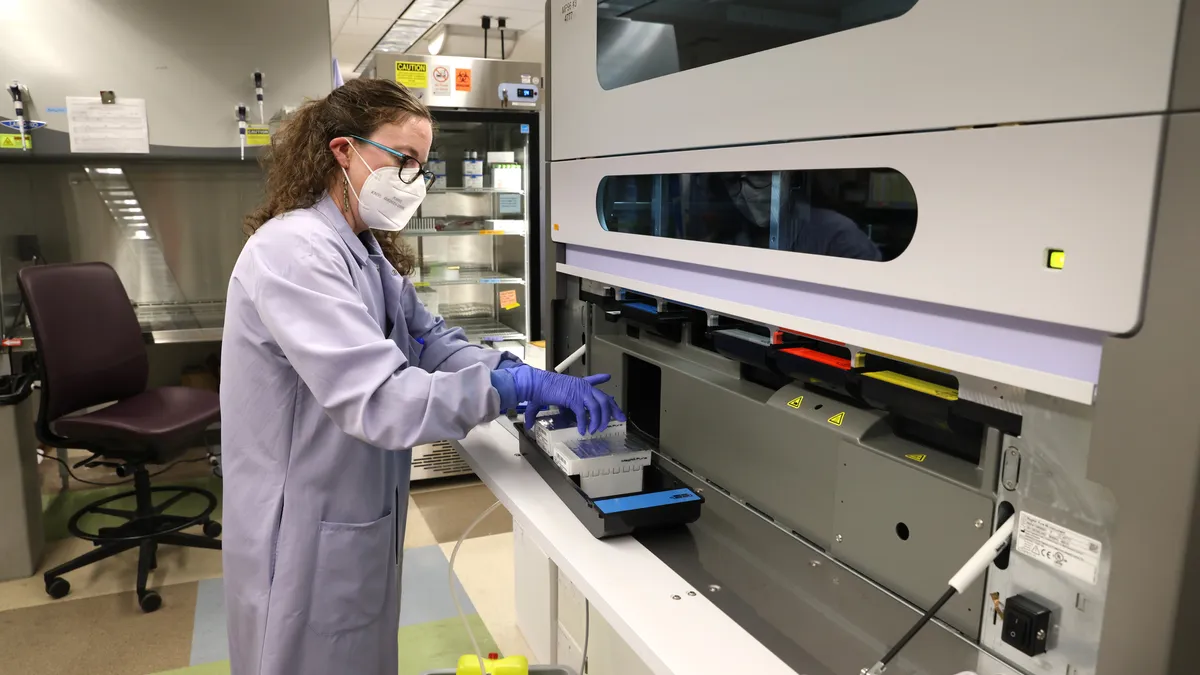 A picture of a researcher standing in front of a testing machine in a laboratory.