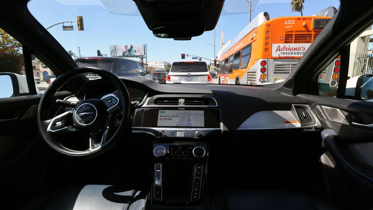 A Waymo self-driving taxi waits in traffic on a Los Angeles street with heavy traffic.