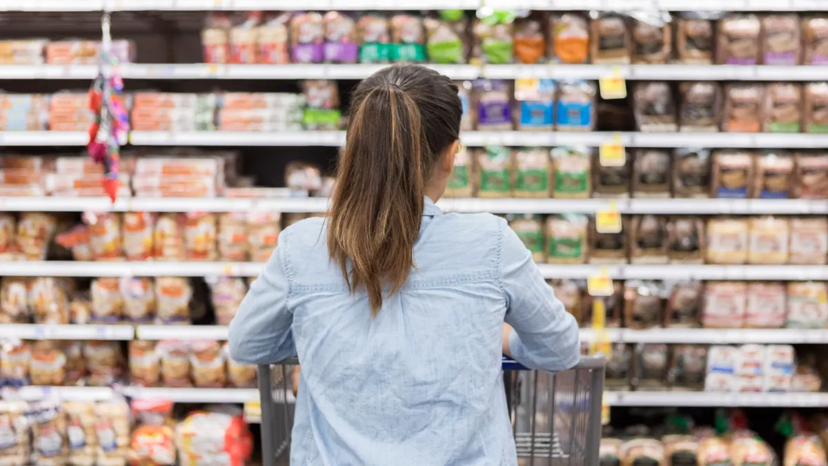 View of woman from behind examining bread aisle at store