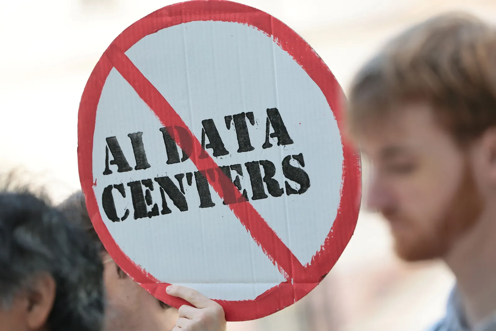 A sign reading "AI Data Centers" with a red line crossing it out.