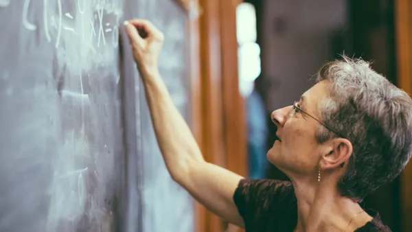 A teacher writes a formula on a chalkboard.