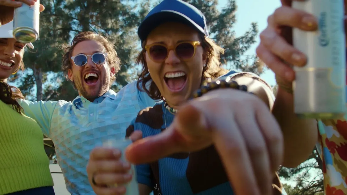 A group of people around a camera drinking beer.