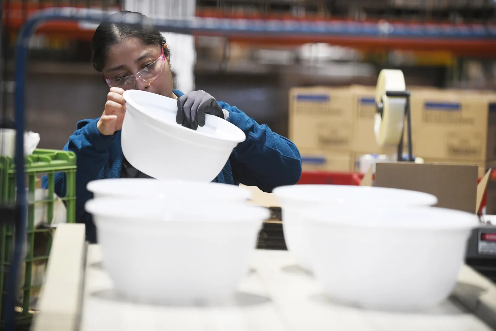 A person in work gear inspects a plastic bowl at Wisconic's injection molding facility