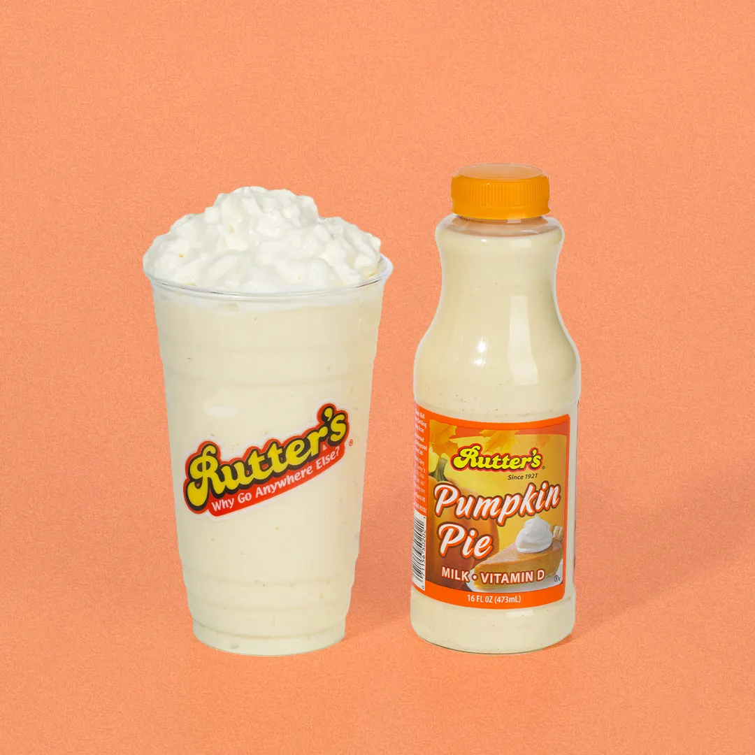 A photo of a milkshake and a bottle of orange milk against an orange background.