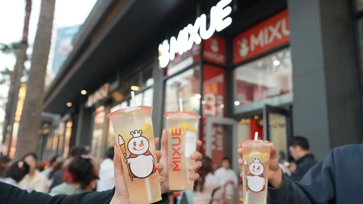An image of arms holding up drinks with a Mixue store in the background