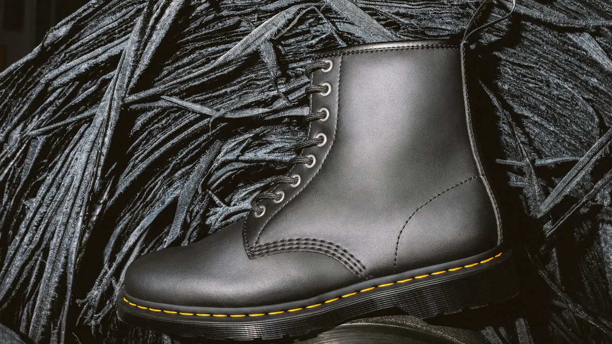 A Dr. Martens leather boot is pictured in front of recycled leather scraps.