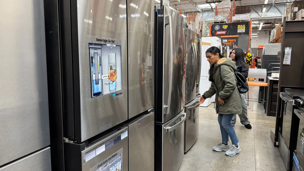 Customers inspect refrigerators at a store.