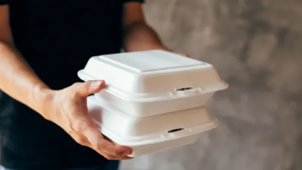 Hands carry styrofoam takeout containers