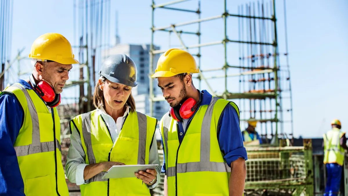 A group of construction workers have a conversation on a jobsite.
