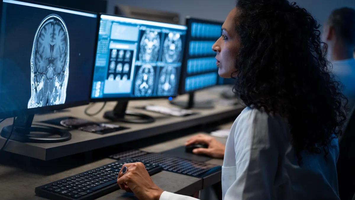 A person looks at a computer screen with images of a person's brain.