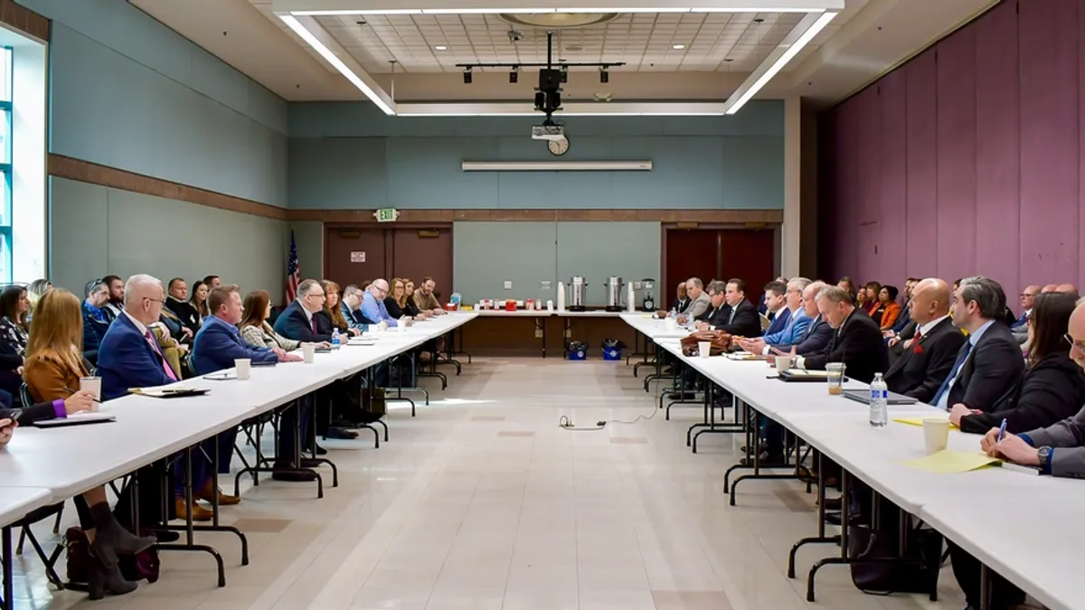 Two rows of tables with people facing each other.