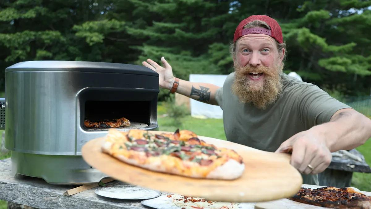 Influencer Zachary Fowler pulls a pizza out of a Solo Stove