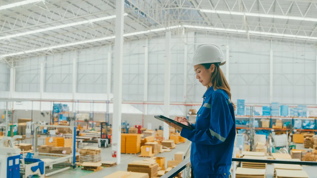Professional Asian female industrial engineers use tablet while standing in manufacturing factory