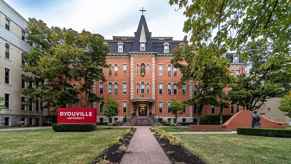Brick building in background with university sign on quad in foreground.