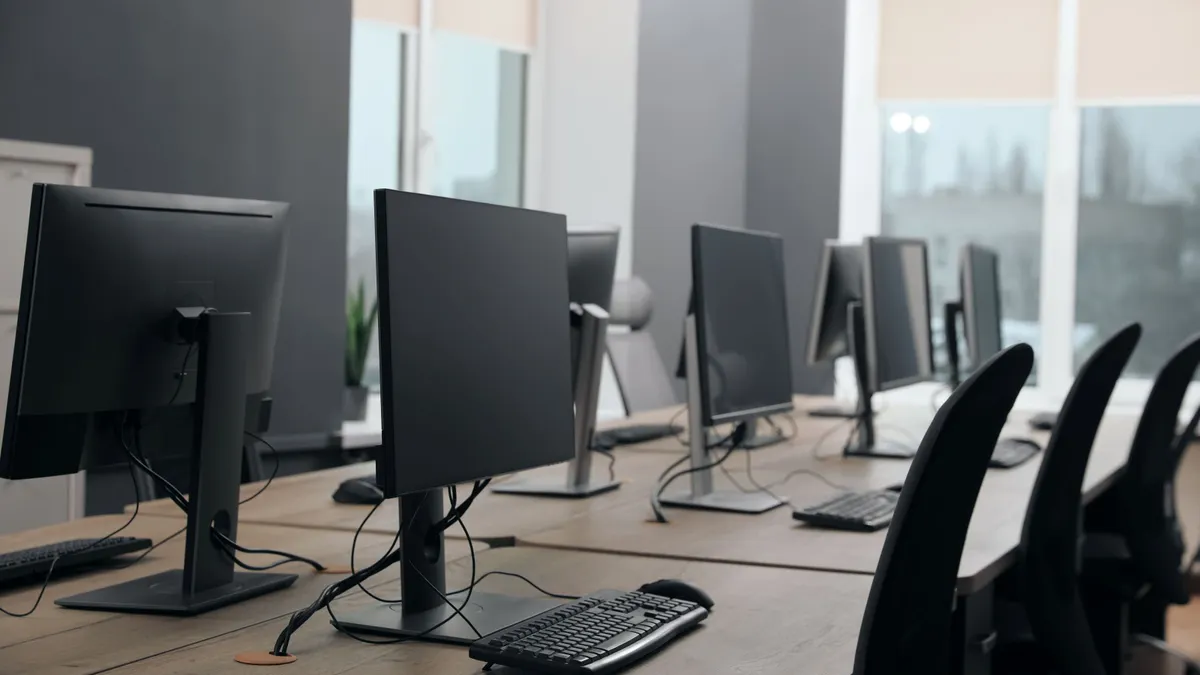 A row of several black office computers.
