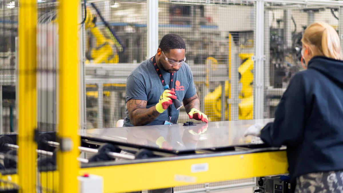 Person at a manufacturing facility creating a solar panel.