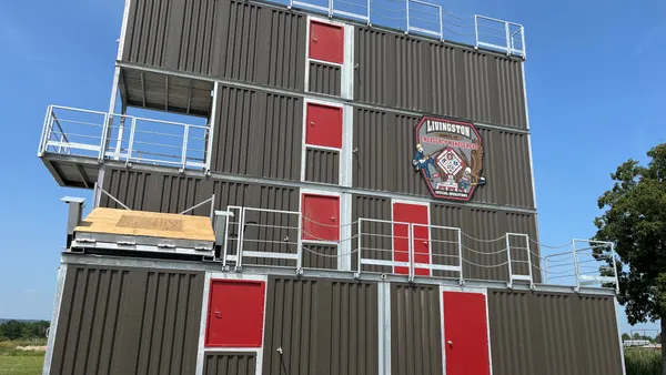 A gray structure with red doors and white gates and a seal that says "Livingston Emergency Management."